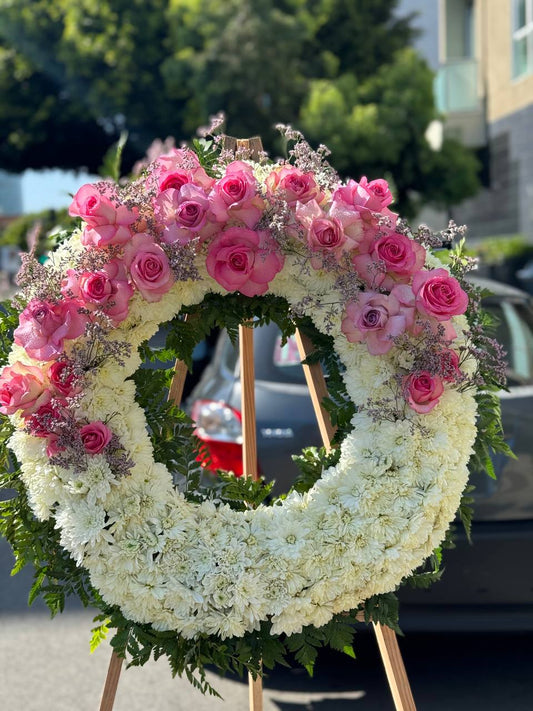 Circular spray bouquet of pink roses and peonies with gold accents, symbolizing unity and romance