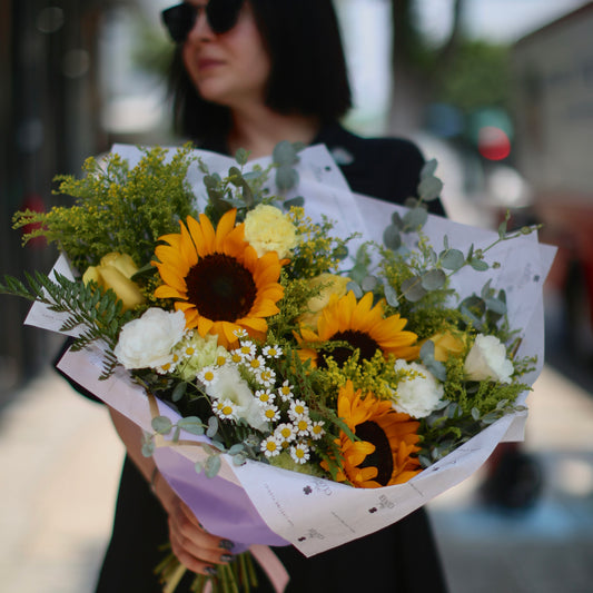 Vibrant Tamara bouquet featuring sunflowers, chrysanthemums and garden roses beautifully arranged in a clear glass vase – ideal for premium floral delivery
