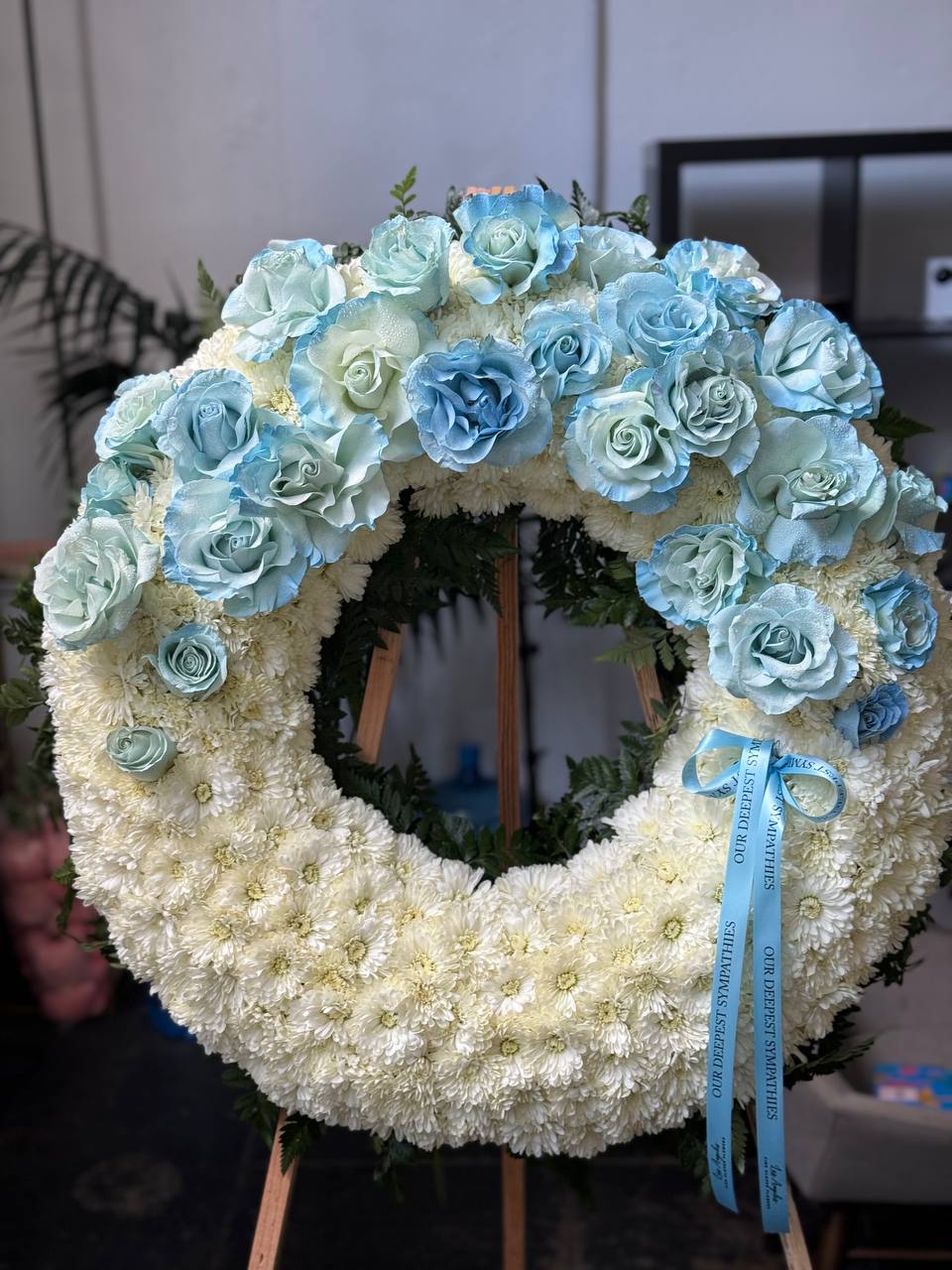 Circular spray bouquet of blue roses and hydrangeas with gold accents, symbolizing unity and serenity