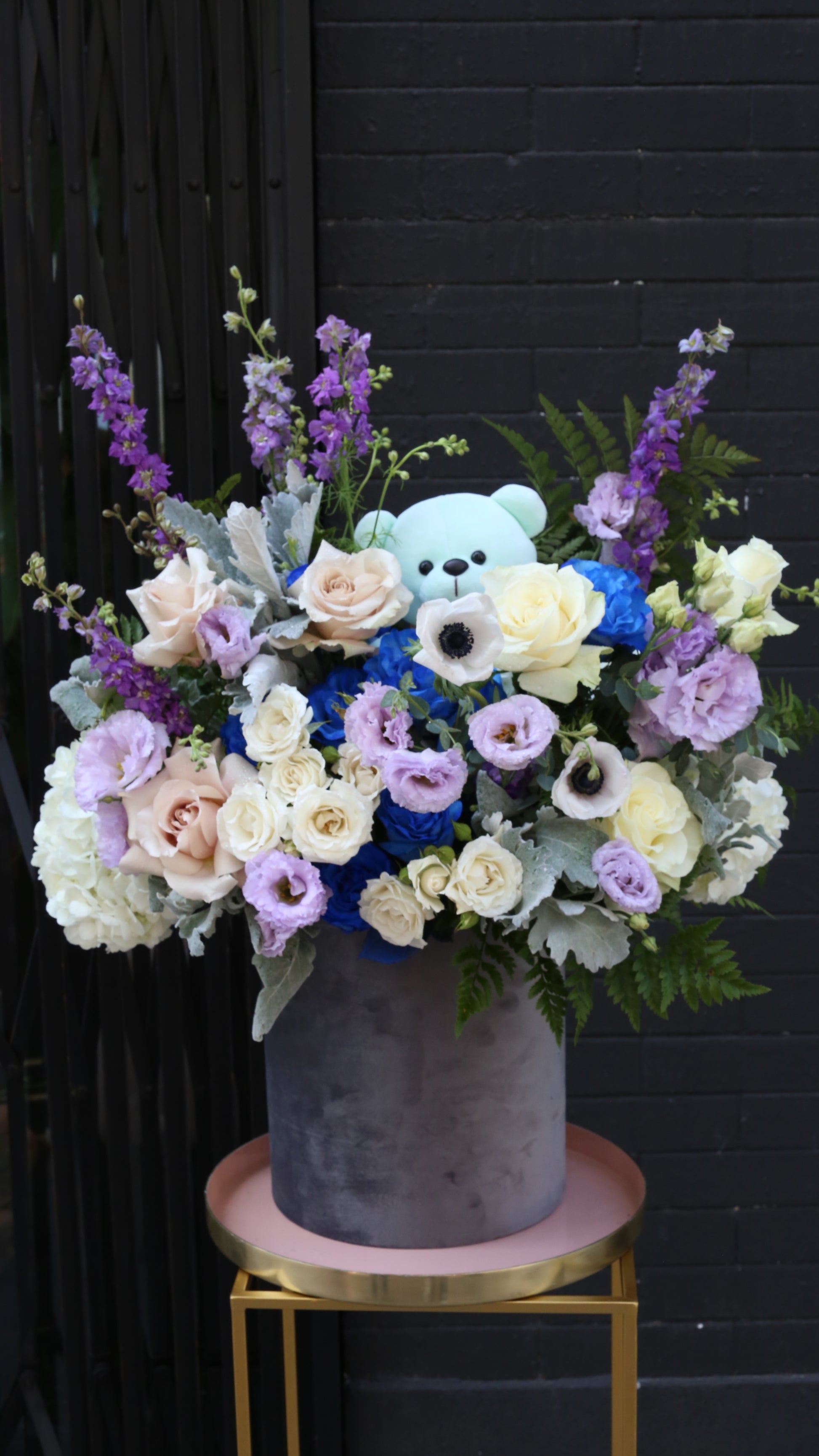 Vibrant Royal Blue Roses paired with soft pink Eustoma and delicate Delphinium blooms in a glass vase.