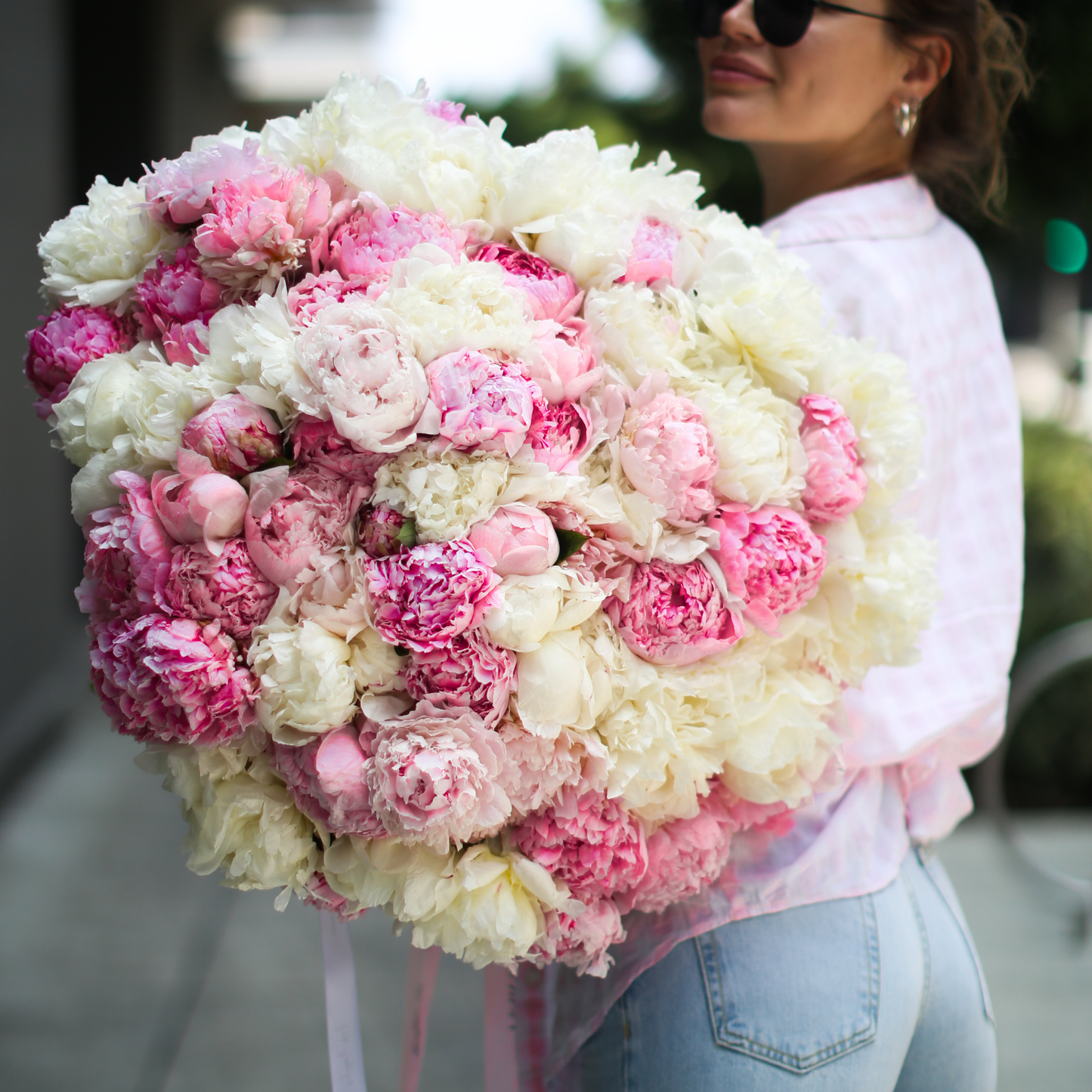 Luxurious arrangement of 100 peonies in blush and white, symbolizing romance and opulence