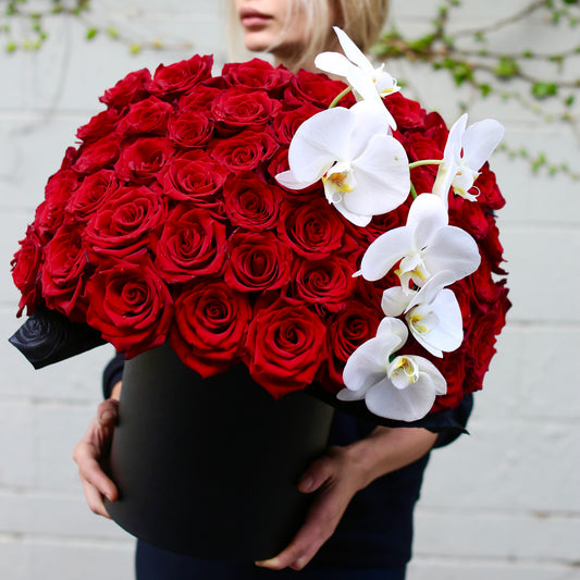 Grand luxury floral arrangement with red roses and white orchids in a premium gift-ready box