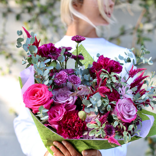 Luxurious Monica bouquet with purple roses and mixed blooms in a clear glass vase, ideal for premium floral gifting