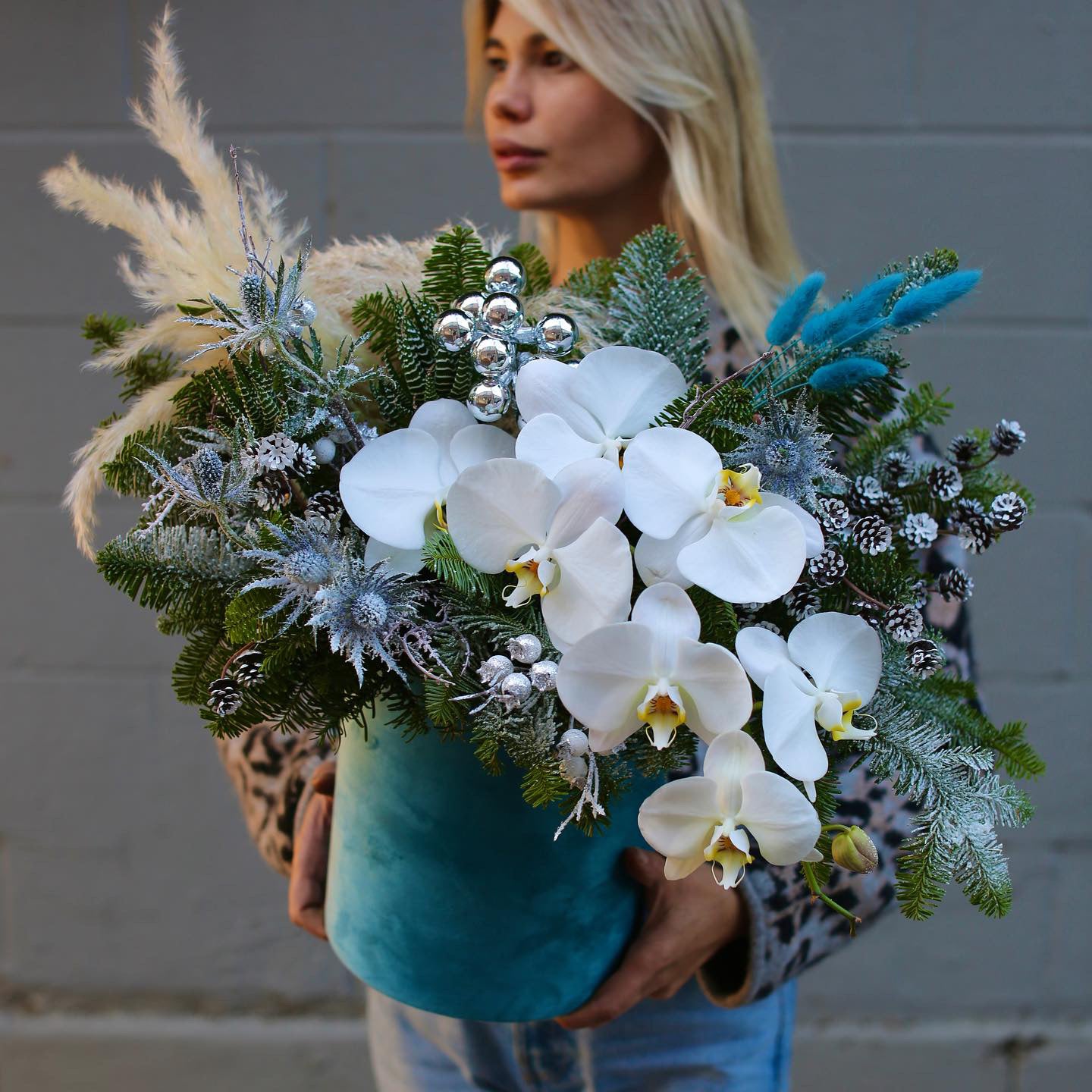 Festive floral design with blue and white tones, showcasing fresh pine and orchids for a luxurious holiday look