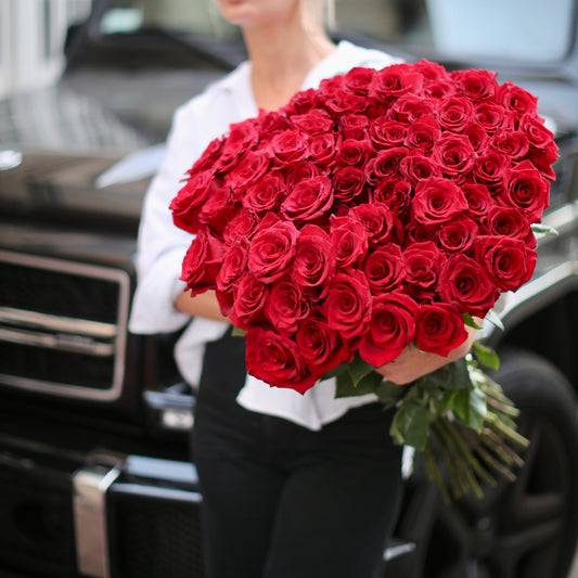Luxurious bouquet of 75 fresh red roses elegantly arranged in a glass vase, ideal for romantic occasions