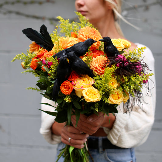 Vibrant Maple Moon bouquet featuring orange roses, yellow spray roses and dahlias accented with black crows – ideal for Halloween floral gifting