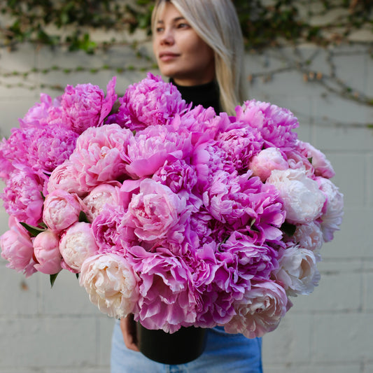 Luxurious peony bouquet in soft pink tones, beautifully arranged in a clear glass vase – ideal for romantic occasions and premium delivery