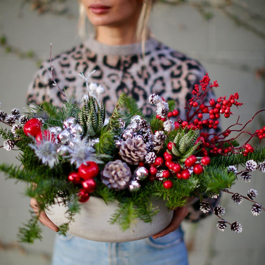 Vibrant Christmas bouquet with red berries, pinecones and frosted foliage, styled for festive holiday gifting