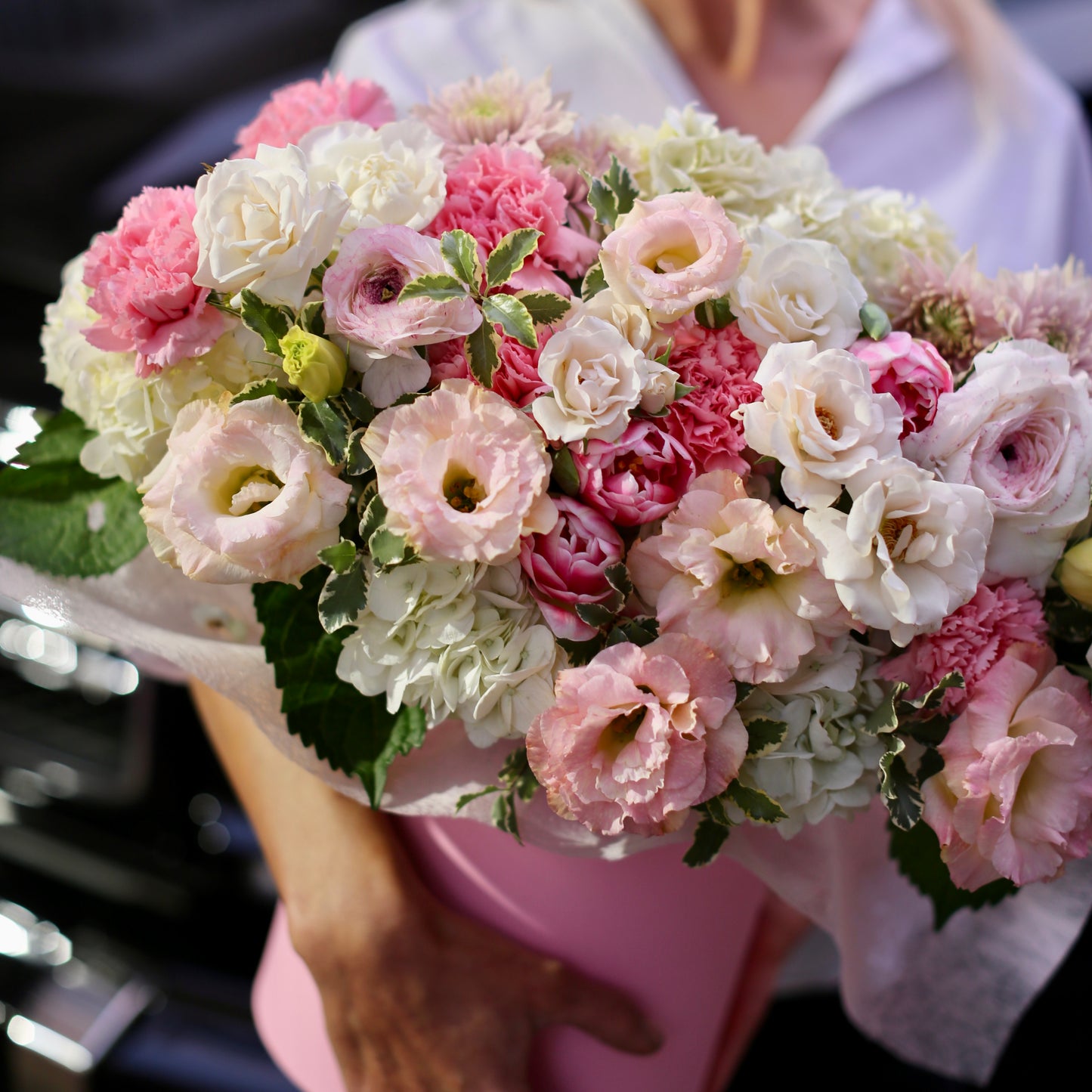 Elegant spring-inspired bouquet styled in a pink box, showcasing fresh ranunculus, roses & carnations for luxury gifting