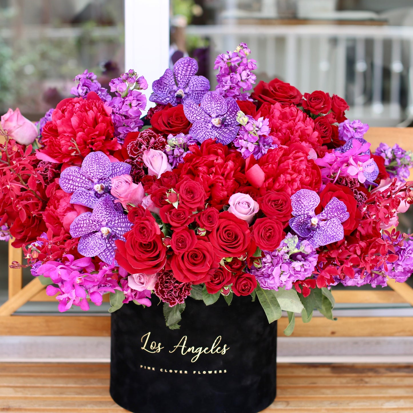 Grand luxury floral arrangement with red roses, peonies, garden roses and multiple orchid varieties in a premium gift-ready box